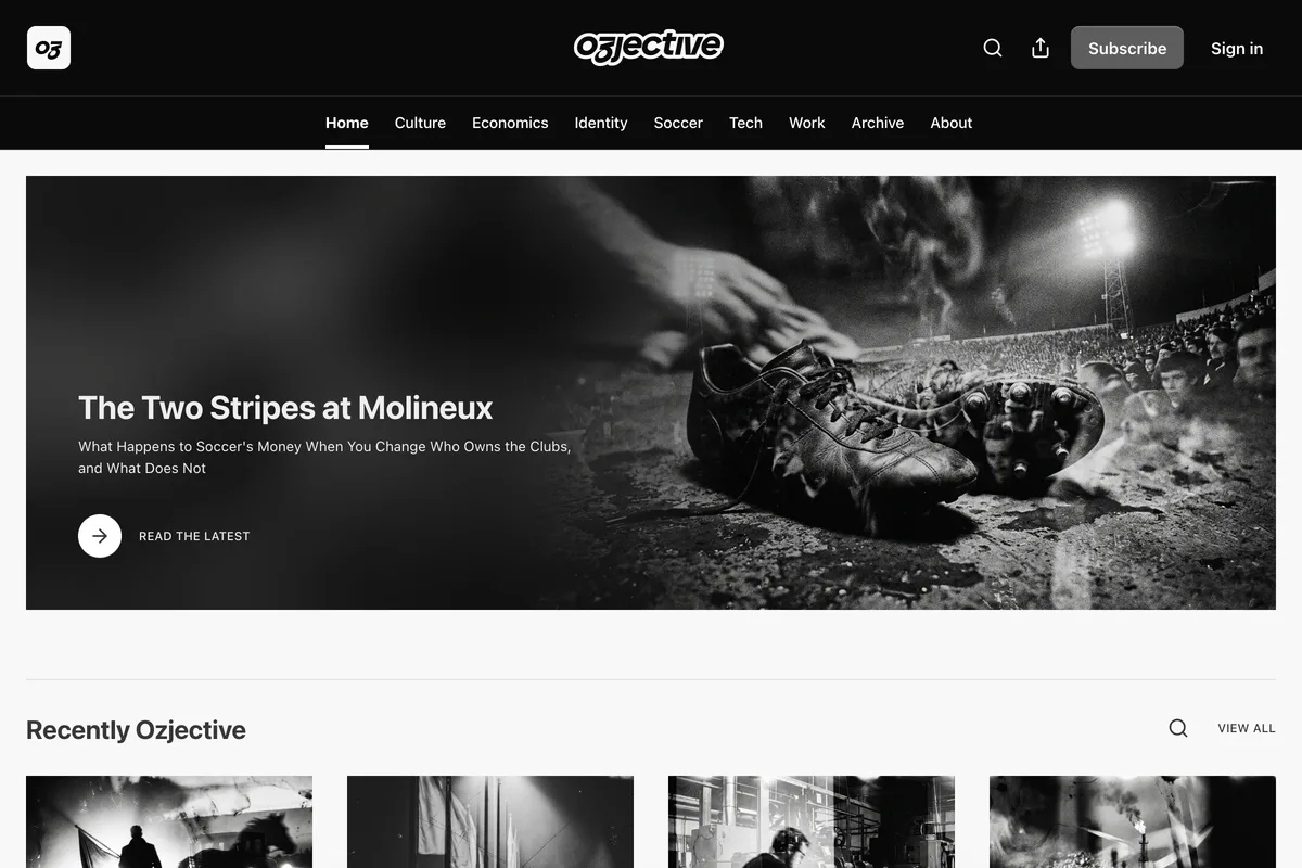 Ozjective homepage on Substack. Black header with the Ozjective wordmark, a Subscribe button and Sign in, above a navigation row reading Home, Culture, Economics, Identity, Soccer, Tech, Work, Archive and About. A wide black and white hero photograph of worn football boots on a floodlit pitch carries the headline The Two Stripes at Molineux, the subtitle What Happens to Soccer's Money When You Change Who Owns the Clubs, and What Does Not, and a Read the Latest link. Below it a Recently Ozjective section opens a row of monochrome article thumbnails.