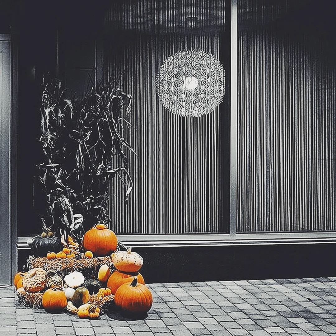 Carved Halloween pumpkins arranged in a shop doorway beneath a large globe pendant light