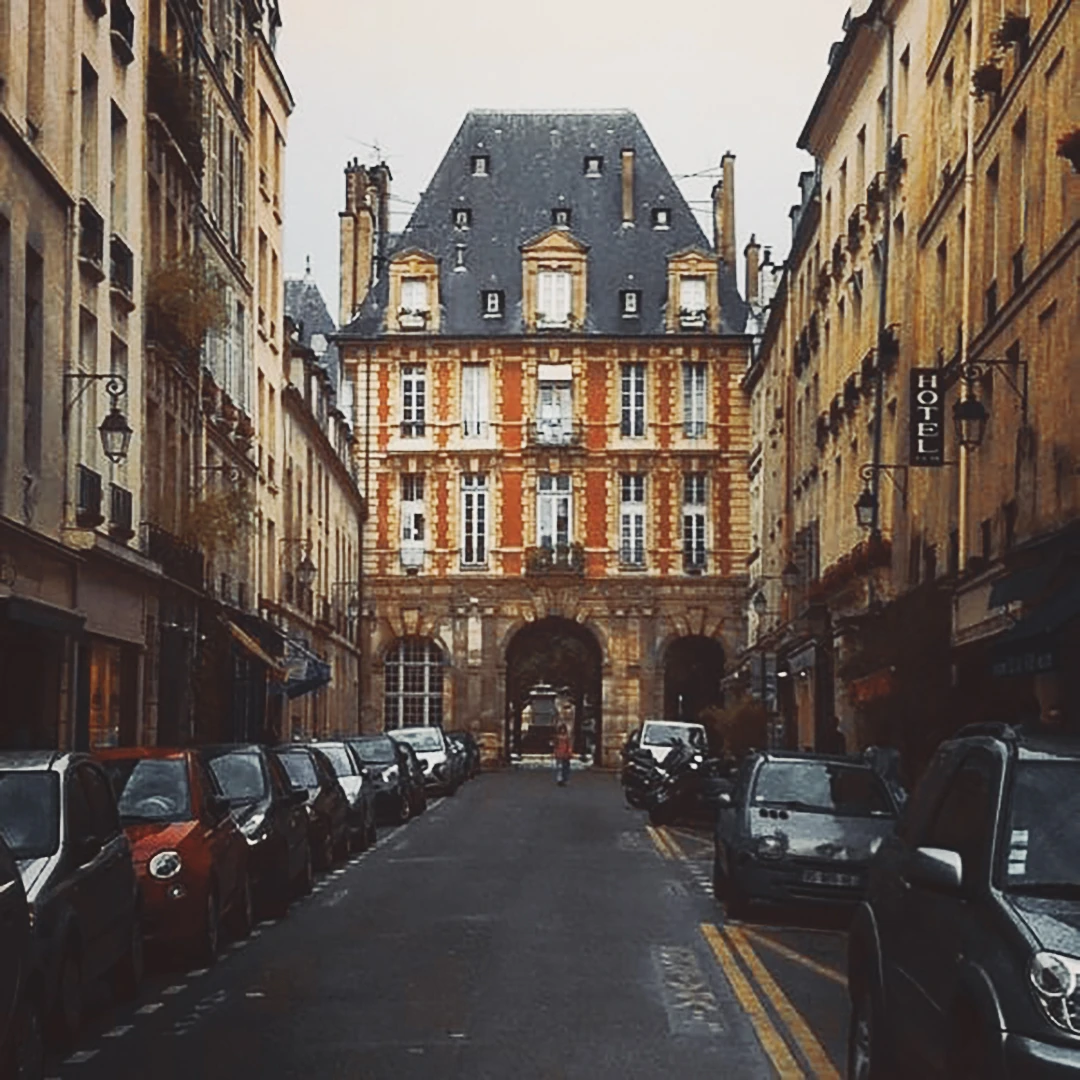 A Parisian street receding toward a grand historic building under an overcast sky