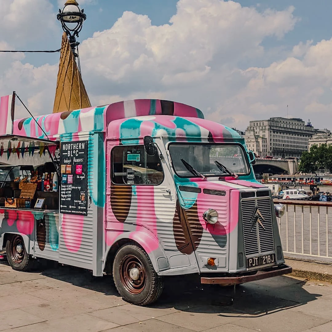 A colourful vintage Citroën H van converted into an ice cream truck parked by the Seine in Paris