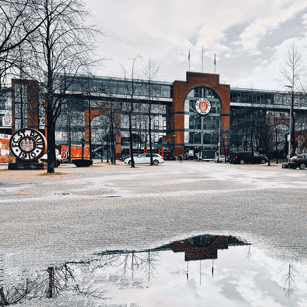 FC St. Pauli facade reflected in a rain puddle on an empty plaza on a grey winter day